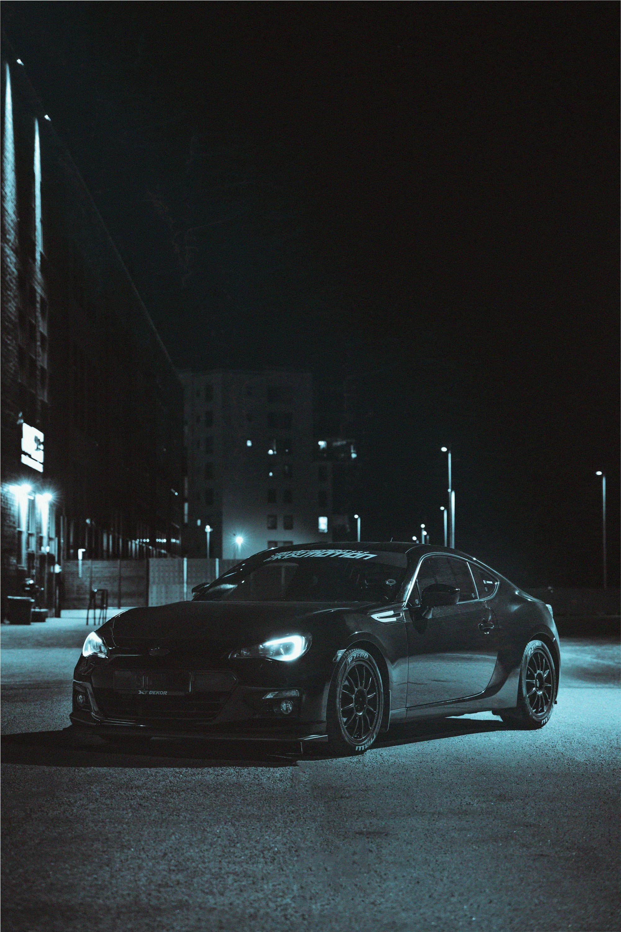 A black sedan on a city road at night